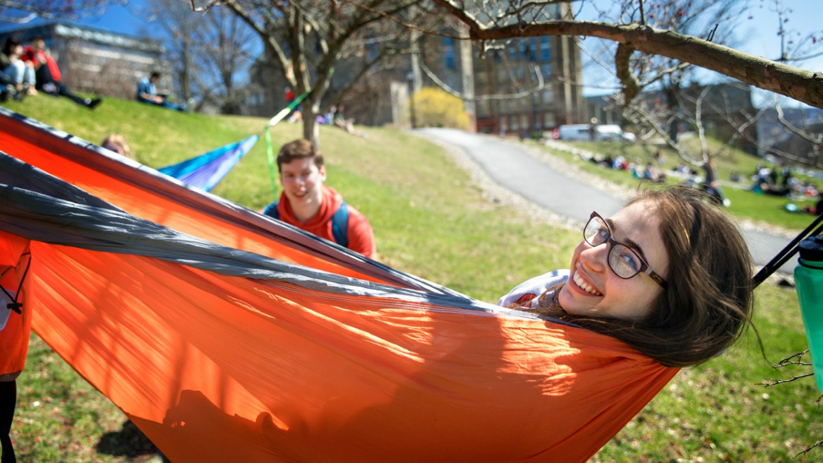 A girl lays in a hammock on campus