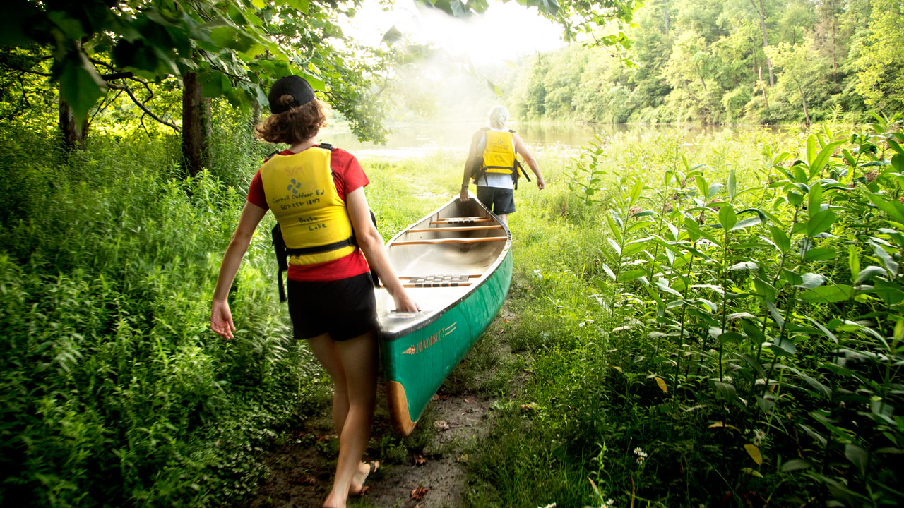 Ttwo people carrying a canoe to Beebe Lake.