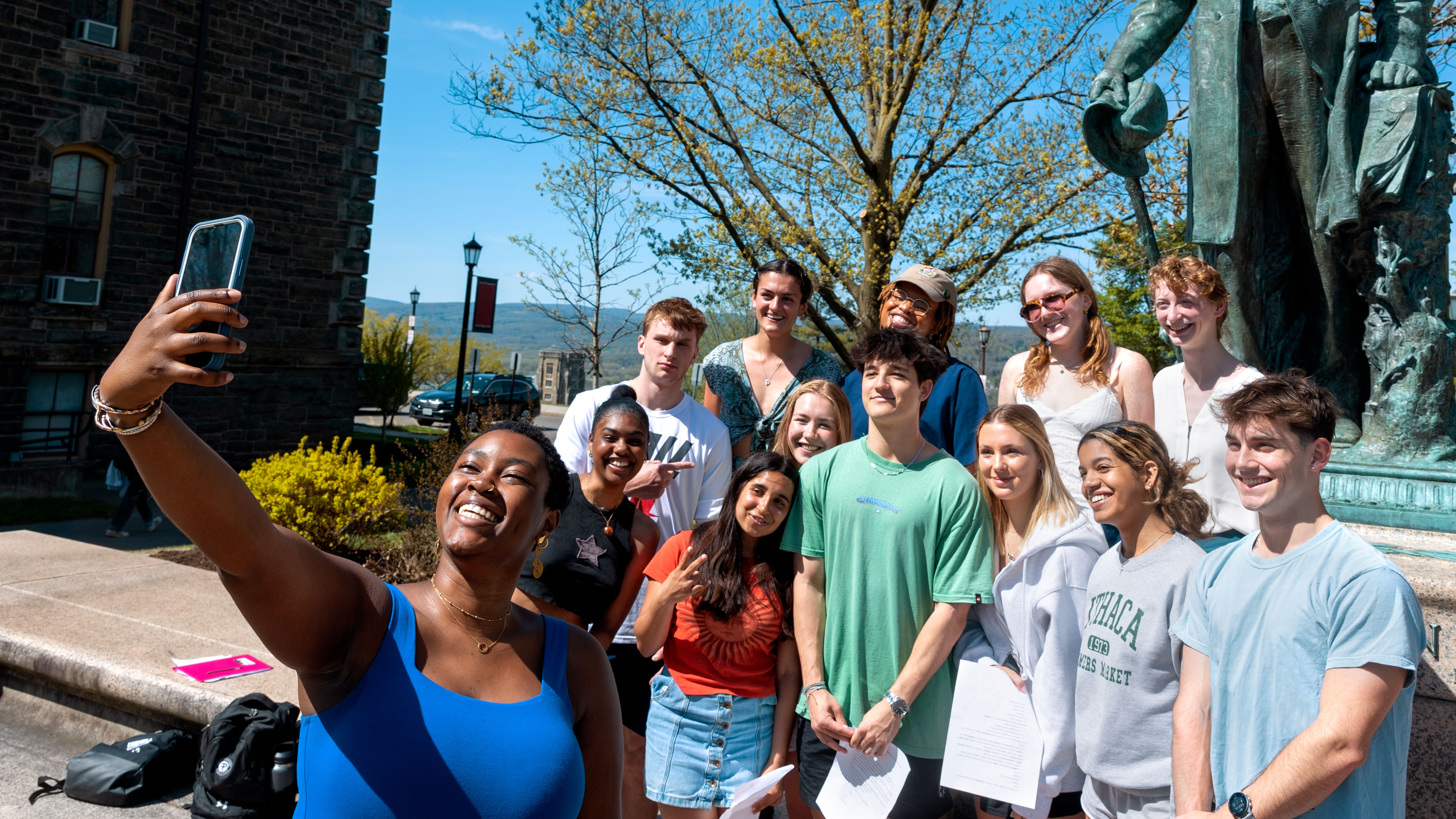 A class gathers for a group photo next to the Ezra Cornell statue.