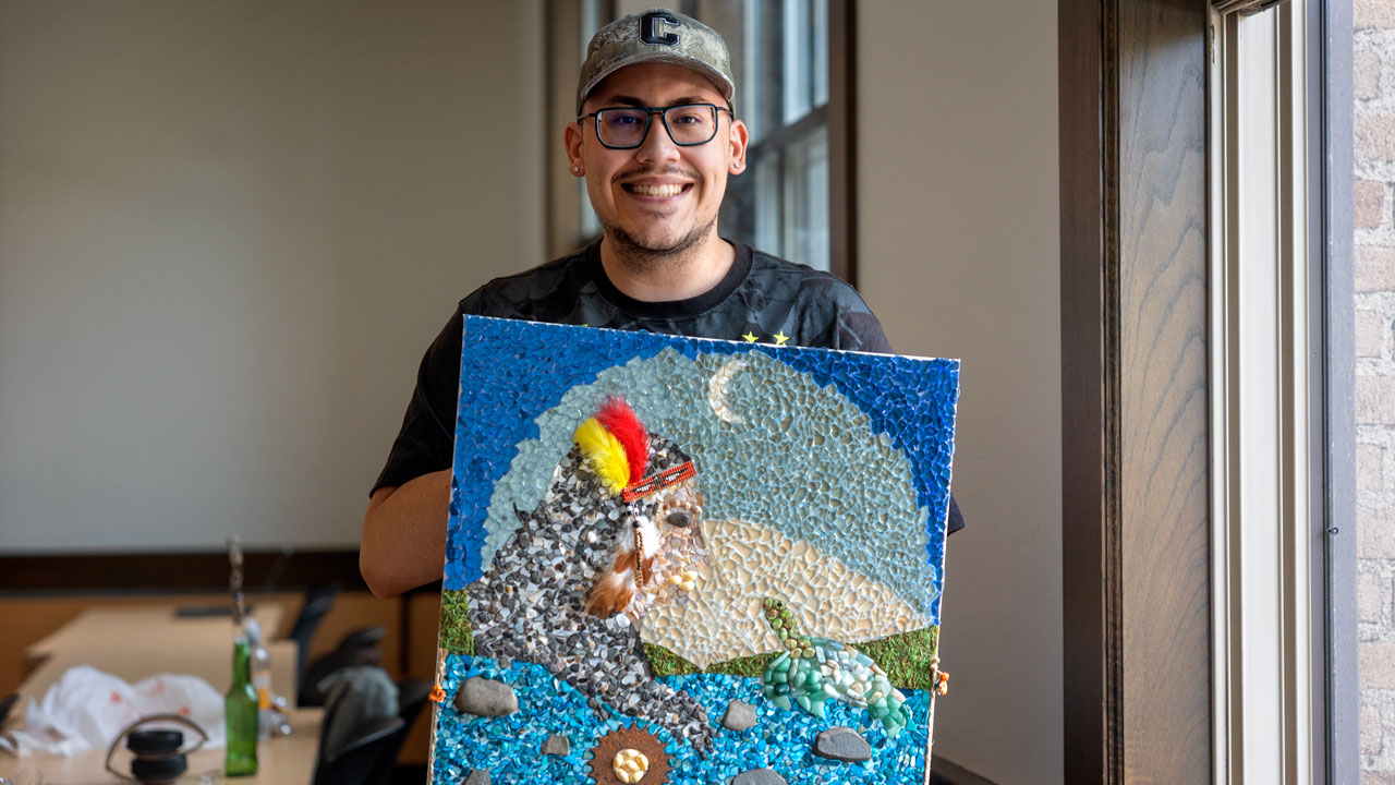 Chris Rivera ’24 holds his mosaic that tells the Haudenosaunee creation story.